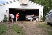 Ann Farkas, left, works with her daughter Alex Farkas and family friend Damian Hartman as they clean up the Farkas home in Canisteo, N.Y., Friday, Aug. 9, 2024, after remnants of Tropical Storm Debby swept through the area, creating flash flood conditions in some areas. (AP Photo/Craig Ruttle)