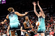 Las Vegas Aces guard Tiffany Hayes (15) is fouled and loses control of the ball as she tries to drive between New York Liberty forwards Nyara Sabally (8) and Breanna Stewart (30) during the first half of a WNBA basketball game Saturday, Aug. 17, 2024, in Las Vegas. (Steve Marcus/Las Vegas Sun via AP)