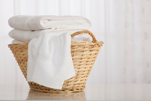 Studio shot of stack of white towels in Wicker Basket