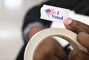 A person holds up an "I voted" sticker during early voting in Onondaga County in 2020.