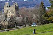 FILE - A Cornell University student walks along the campus in Ithaca, N.Y., on Dec. 16, 2021, with luggage in tow. (AP Photo/Heather Ainsworth, File)